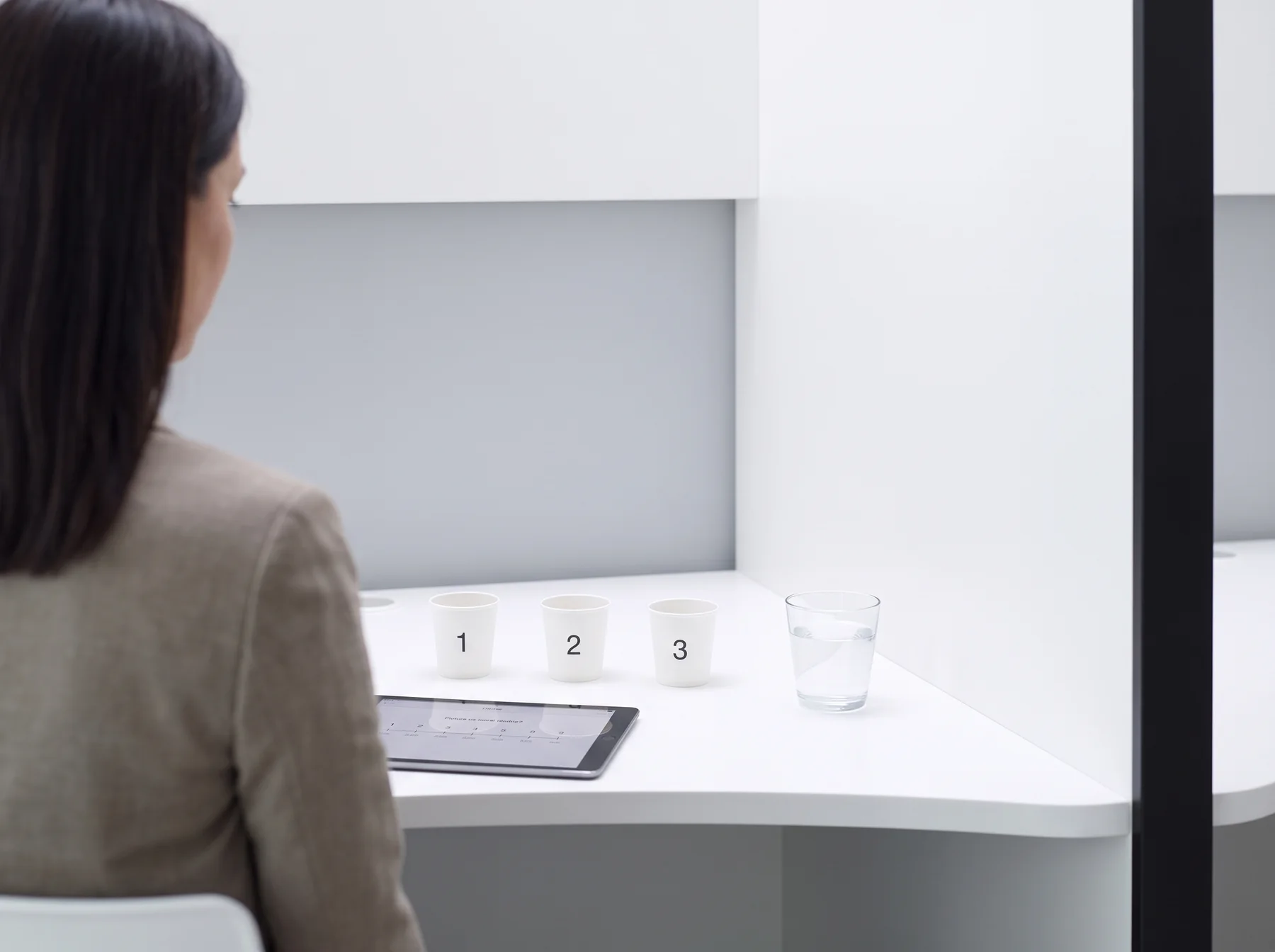 Blick in eine SCS-Kabine: Probenbecher, Wasser und Tablet mit Bewertungsskala